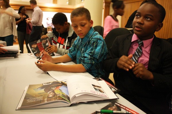 Students who were interviewed for the “Griots of Oakland” sign the covers of the book.